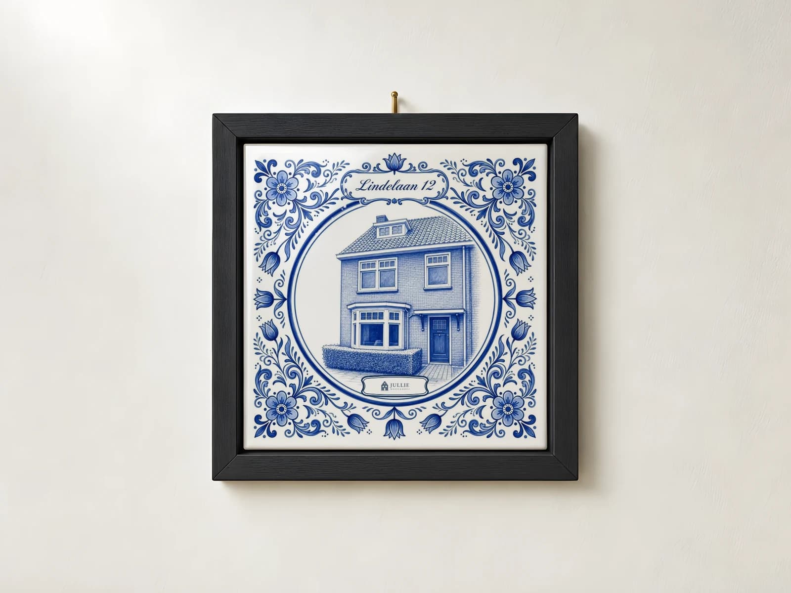 Delfts blauw tegeltje van een woning in een zwarte lijst